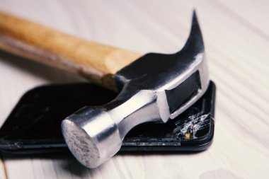 Çekiç ve ezilmiş telefon masada.