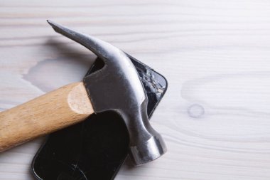 Çekiç ve ezilmiş telefon masada.