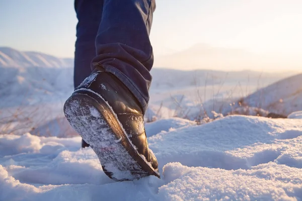 men\'s feet in boots in the snow walking in winter