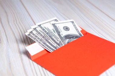 Tahta bir masanın üzerindeki zarfın içinde Amerikan doları. Gelir, ikramiyeler veya rüşvet konsepti.