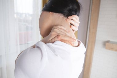 Boynuna masaj yapan bir kadının eline yakın çekim. Kızın boynu ağrıyor.