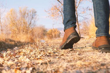 Dışarıda yürüyen bir adamın bacakları. Arka planda yaşam tarzı moda modası sonbahar sezonu doğası.