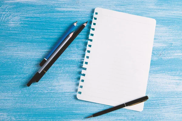 Masanın üzerinde kalemler olan bir defter.