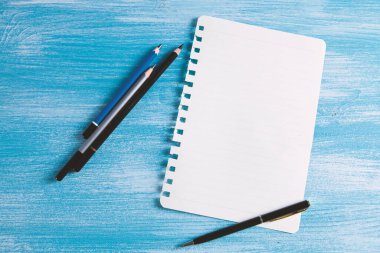 Masanın üzerinde kalemler olan bir defter.