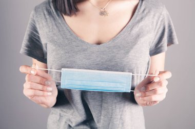 Elinde tıbbi maske tutan bir kız.