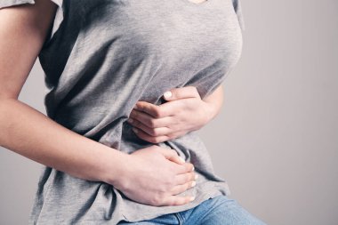 Yatakta yatan kız mide ağrısı çekiyor.