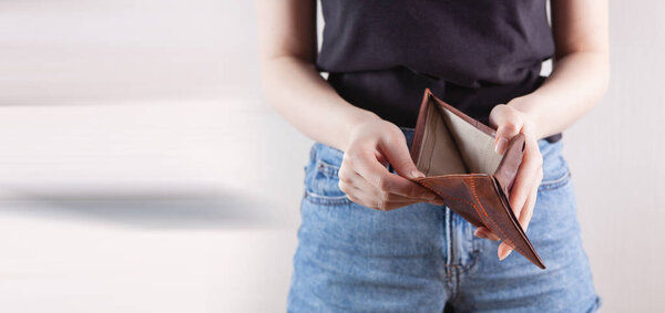 Девушка держит пустой бумажник в руке