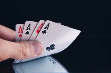 Kağıt oynayan dört aslı poker eli.