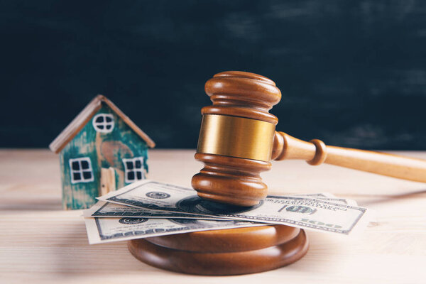 Judge gavel and houses on a wooden background. The concept of a real estate auction or division of a house in case of divorce.