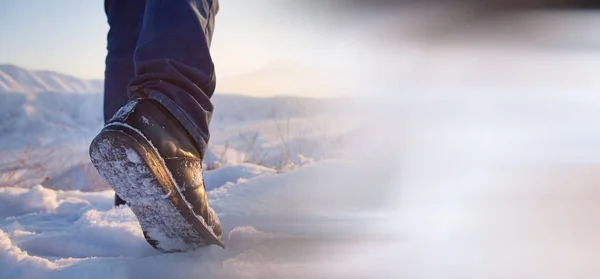 men\'s feet in boots in the snow walking in winter