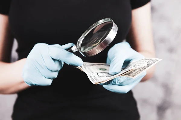 girl checks money with a magnifying glass