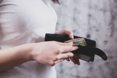 Kız cüzdanı elinde tutuyor ve parayı alıyor.