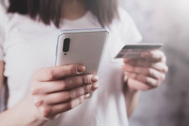 Elinde telefon ve banka kartı olan bir kız.