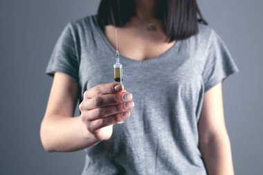 Eldivenli kız elinde şırınga tutuyor.