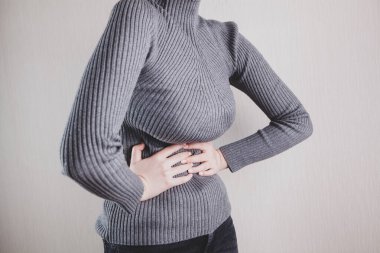 Yatakta yatan kız mide ağrısı çekiyor.