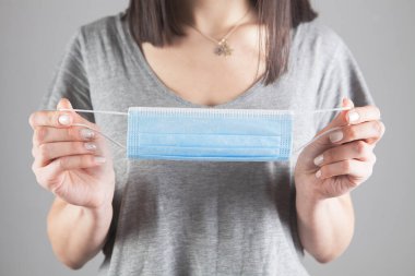 Elinde tıbbi maske tutan bir kız.