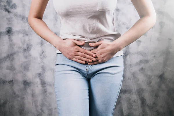 Yatakta yatan kız mide ağrısı çekiyor.