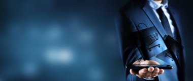 Adamın biri mavi arka planda telefonla online alışveriş yapıyor.