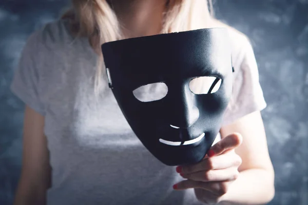 woman holding black plastic mask on gray background