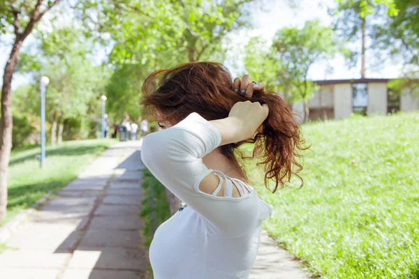 公園で髪を矯正する若い女性は — ストック写真