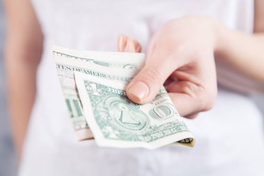 Genç kadın gri arka planda para veriyor.