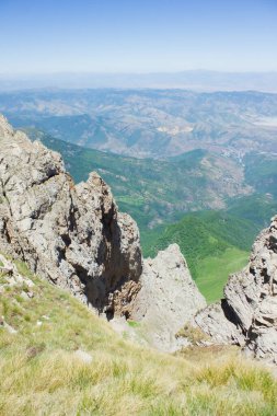 Dağdan görünen mavi gökyüzünün altındaki kayaların arasından