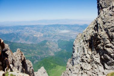 Dağdan görünen mavi gökyüzünün altındaki kayaların arasından