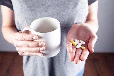 Genç kız bir çalar saat ve ilaç tutuyor. Yukarıdan görünüm