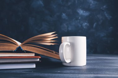 Açık bir kitap ve masada bir fincan.