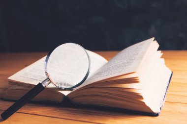 Kitap ve büyüteç masanın üstünde. arama ve çalışma konsepti