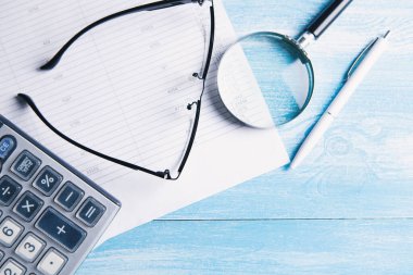 Kağıt, hesap makinesi, büyüteç ve bardaklar masaya. masaüstü konsepti