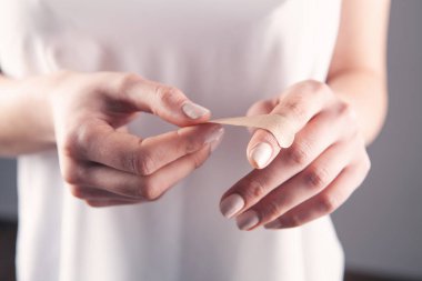 Genç bir kadın parmağına sıva yapıyor.