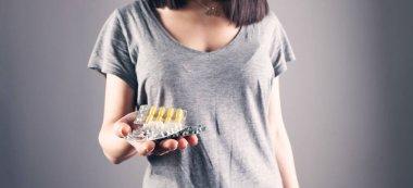 Elinde haplar tutan genç bir kadın.