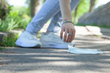 Yerden tıbbi bir maske kaldırır.