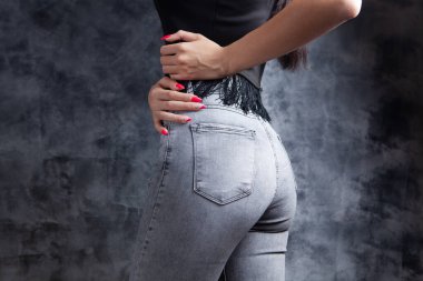 Genç kadın gri arka planda geriye doğru duruyor.