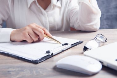 Bir kadın dizüstü bilgisayarın önünde oturuyor ve belgeleri inceliyor.