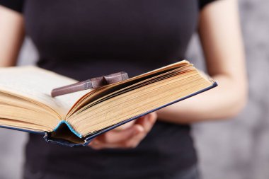 Elinde kitap ve tahta haç tutan bir kız.