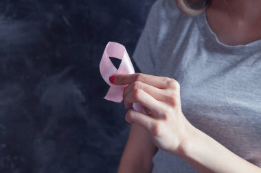 Genç kız pembe kurdele tutuyor.