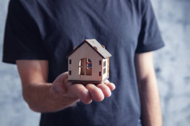 Elinde ev tutan genç bir adam.