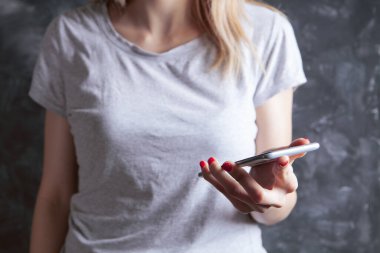 Genç bir kız elinde telefonla dikiliyor.