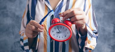 Diş fırçası ve çalar saat tutuyor.