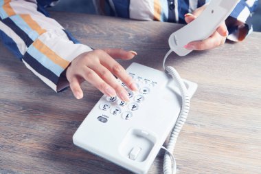 Genç bir kadın ev telefonuyla arıyor.