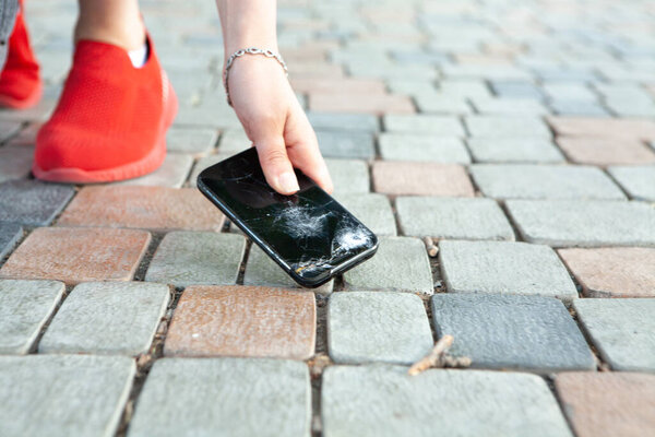 поднимает сломанный телефон с земли