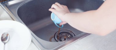 Genç kız mutfakta bulaşıkları yıkıyor.