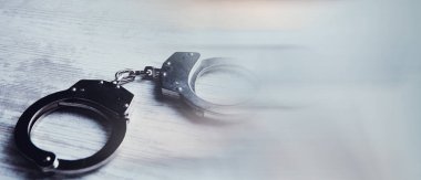 Tahta bir masaya kelepçelenmiş.