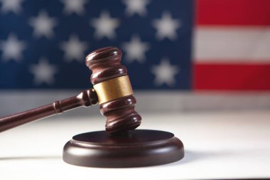 Tahta hakimin tokmağı masada, arka planda ABD bayrağı var.