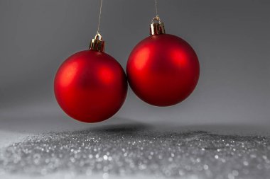 Gümüş parıltılı arka planda iki kırmızı noel topu, yakın plan.