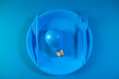 Mavi tabakta çatal bıçaklı ampul, fikir konsepti.