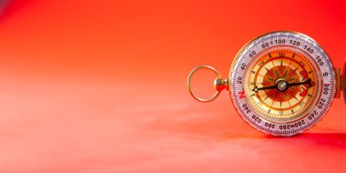 Kırmızı arka planda pusula. Seyahat ve navigasyonun kavramsal görüntüsü.
