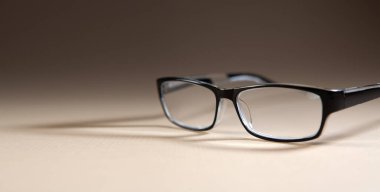 Bej arkaplanda siyah çerçeveli gözlük. Yakın plan.